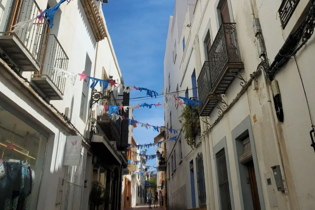moraira old town street (1) A view along one of the narrow streets in Moraira's old town with coloured flags hanging between the buildings