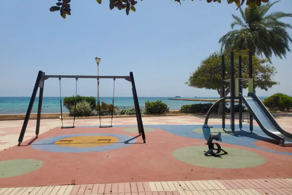 santa pola park Swinds and a slide in a childrens playpark looking out over the sea