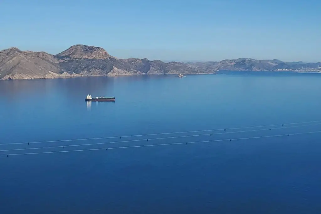 A view of the sea and mountains from Cabo Tiñoso, with a boat in the sea.